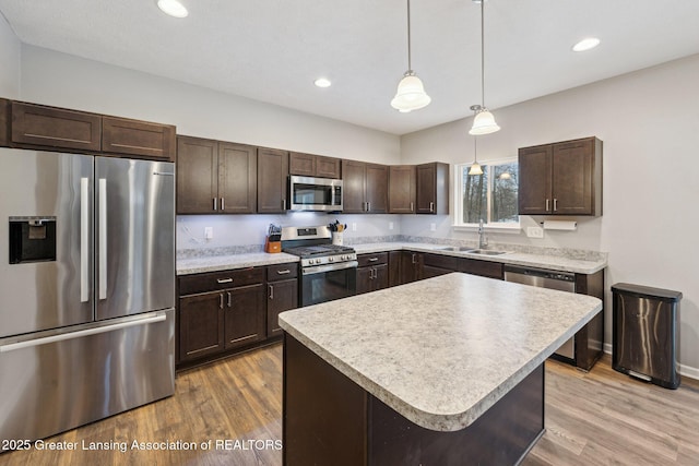 kitchen featuring dark brown cabinetry, sink, a center island, hanging light fixtures, and stainless steel appliances