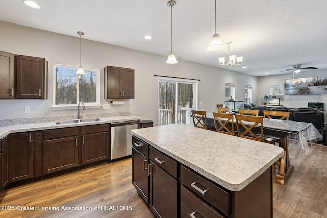 kitchen featuring sink, hardwood / wood-style flooring, stainless steel dishwasher, a kitchen island, and pendant lighting