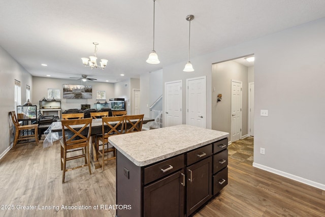 kitchen featuring a kitchen island, hardwood / wood-style floors, decorative light fixtures, ceiling fan, and dark brown cabinets