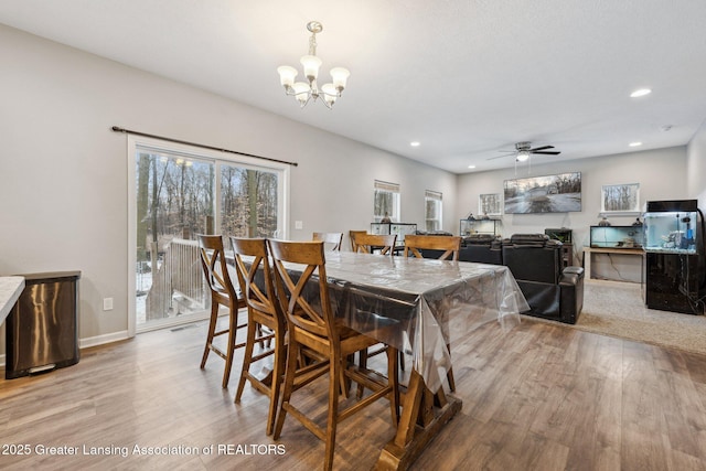 dining room with ceiling fan with notable chandelier and light hardwood / wood-style flooring