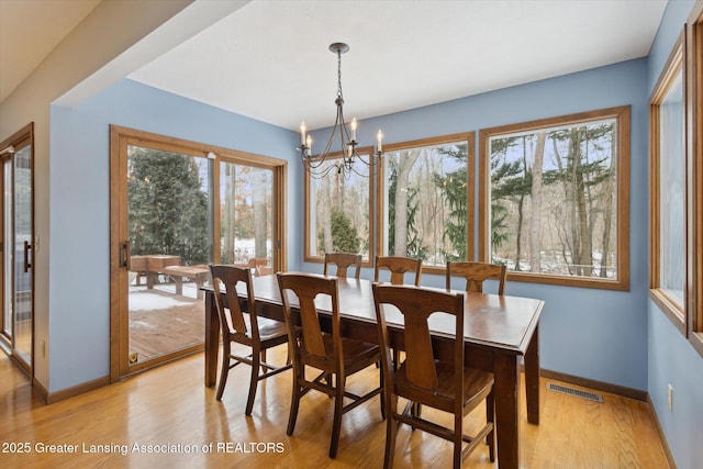 dining room with plenty of natural light, a notable chandelier, and light hardwood / wood-style floors