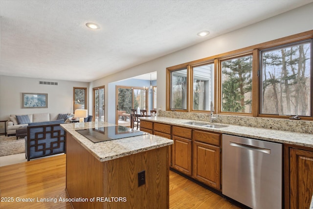 kitchen with a kitchen island, sink, black electric stovetop, stainless steel dishwasher, and light hardwood / wood-style floors