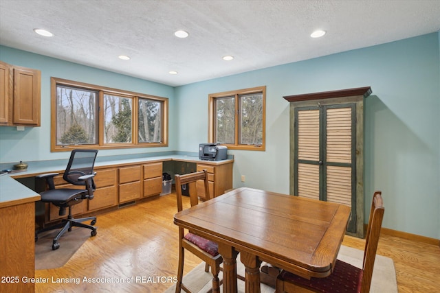 home office with a textured ceiling and light wood-type flooring