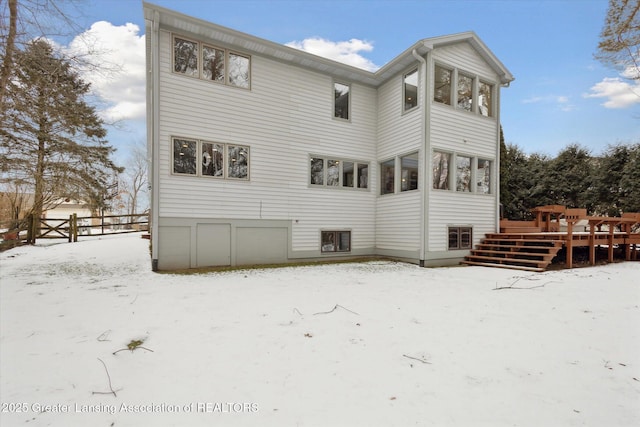 snow covered back of property with a deck