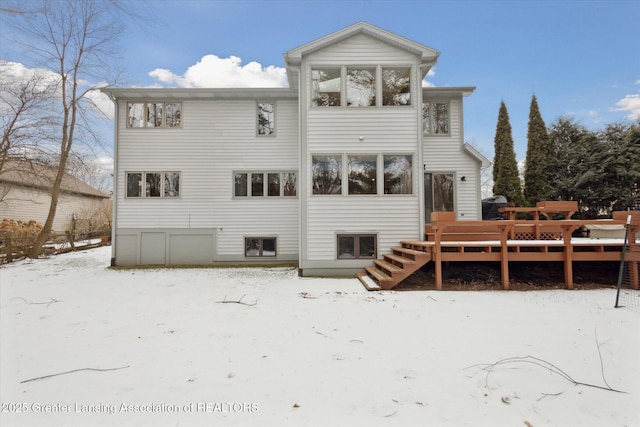 snow covered back of property featuring a deck