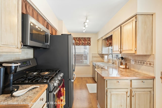 kitchen featuring light brown cabinetry, sink, light hardwood / wood-style flooring, stainless steel appliances, and decorative backsplash