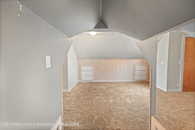 additional living space featuring lofted ceiling, wooden walls, and light carpet