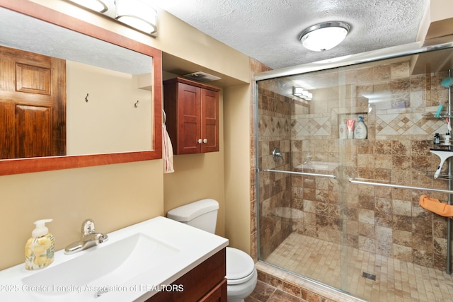 bathroom with a shower with door, vanity, a textured ceiling, and toilet