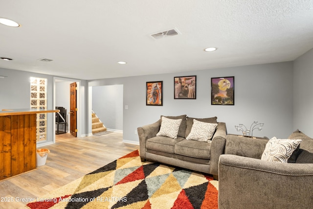 living room with bar, a textured ceiling, and light wood-type flooring