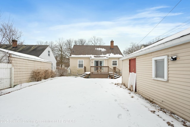 snow covered house featuring a wooden deck