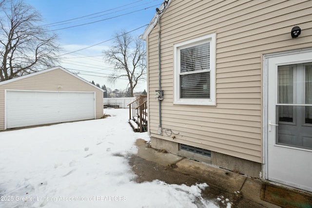 snow covered property with a garage and an outdoor structure