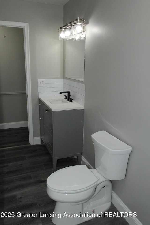 bathroom featuring vanity, backsplash, wood-type flooring, and toilet