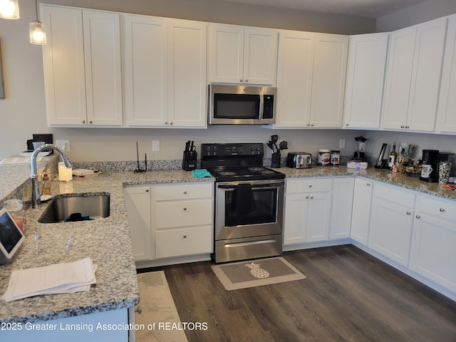 kitchen with hanging light fixtures, stainless steel appliances, sink, and white cabinets