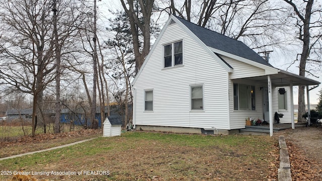 view of home's exterior featuring a porch, a lawn, and a shed