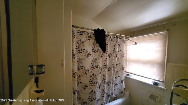 bathroom with shower / tub combo with curtain and tile walls