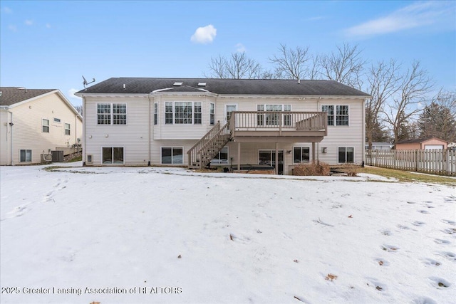 snow covered back of property with central AC unit and a deck