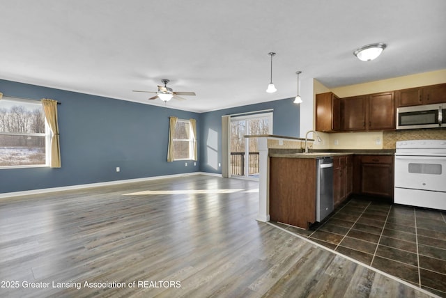 kitchen featuring sink, appliances with stainless steel finishes, dark hardwood / wood-style floors, decorative light fixtures, and kitchen peninsula