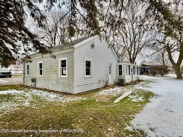 snow covered property featuring central AC unit and a yard