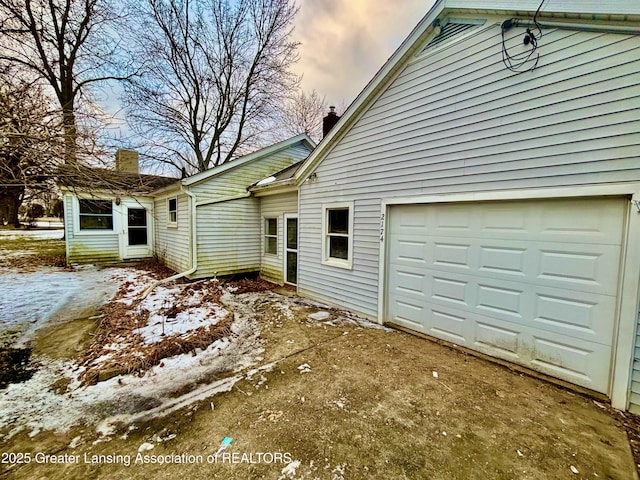 view of snow covered exterior featuring a garage