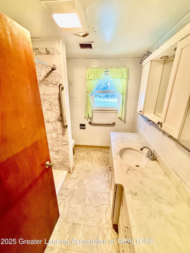 bathroom featuring vanity, tiled shower, and toilet