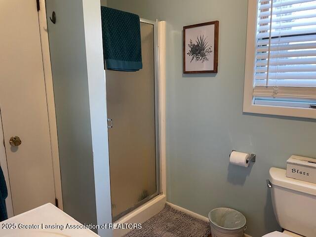 bathroom featuring baseboards, a shower stall, and toilet