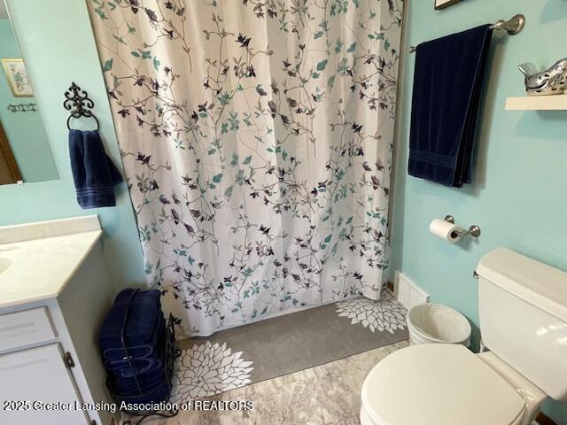 bathroom featuring a shower with shower curtain, vanity, and toilet