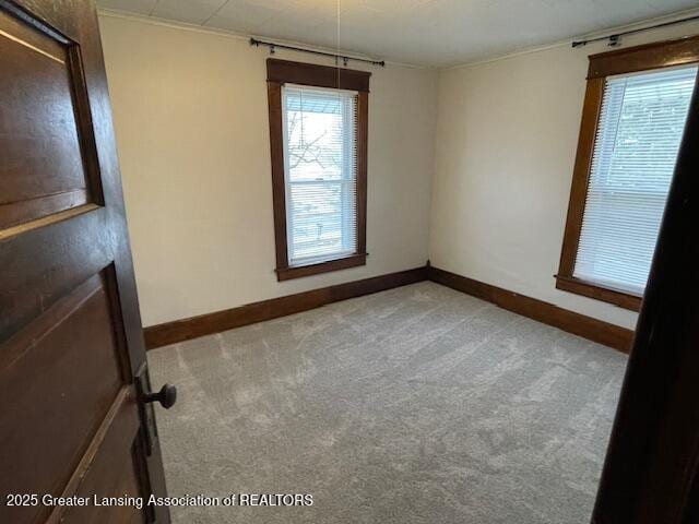 carpeted spare room featuring baseboards