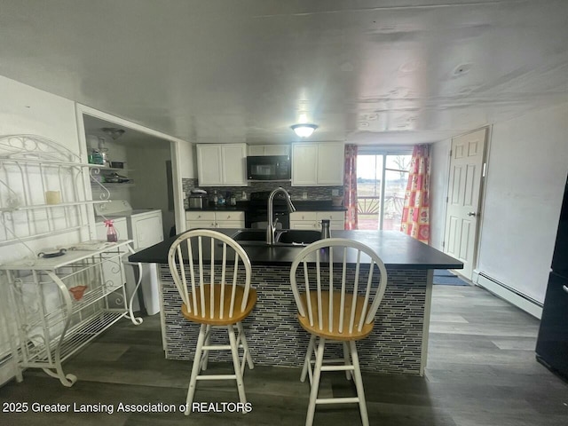 kitchen with baseboard heating, hardwood / wood-style flooring, separate washer and dryer, and white cabinets