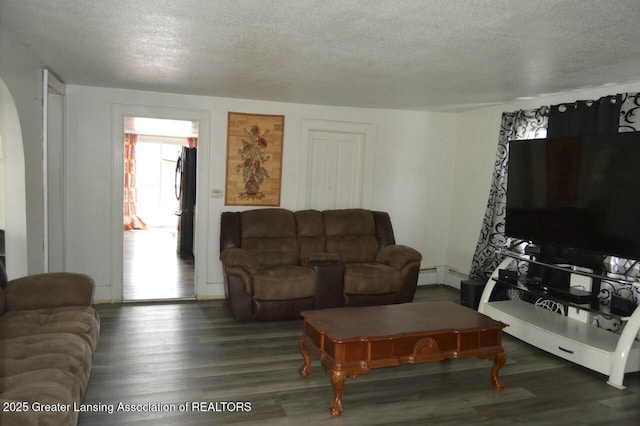 living area featuring a textured ceiling, a baseboard heating unit, and dark wood finished floors