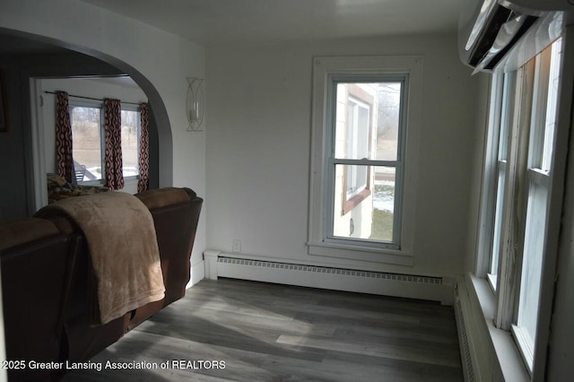 bedroom with multiple windows, dark hardwood / wood-style floors, and baseboard heating