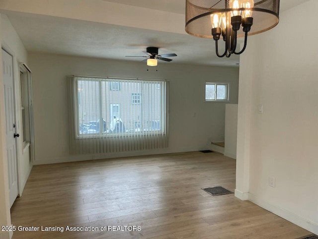 interior space featuring ceiling fan with notable chandelier and light hardwood / wood-style flooring