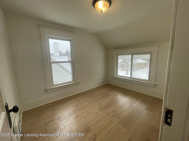 bonus room with lofted ceiling and light wood-type flooring