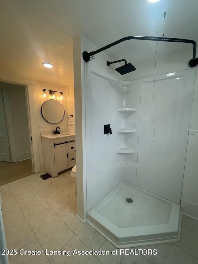 bathroom featuring vanity, tile patterned flooring, toilet, and walk in shower