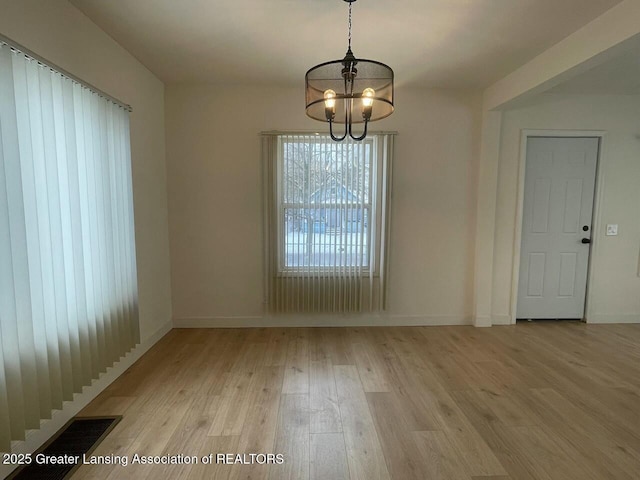 unfurnished dining area with light hardwood / wood-style floors and a notable chandelier