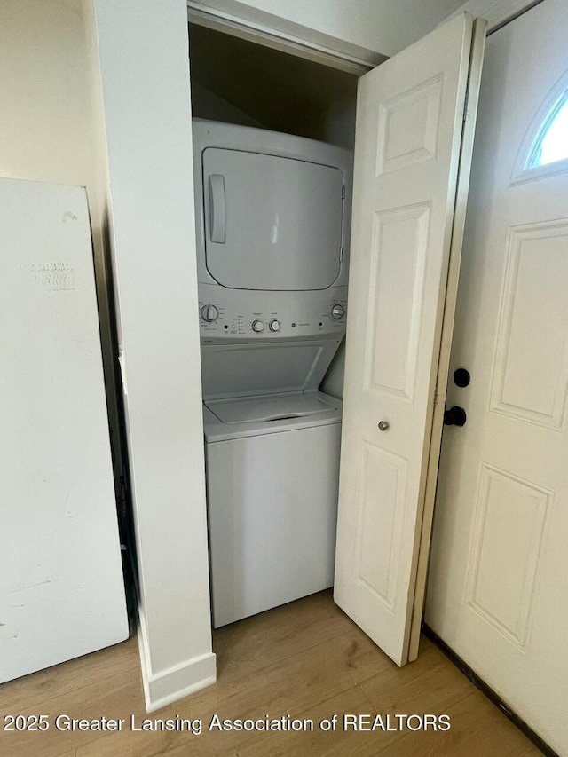 washroom with light hardwood / wood-style floors and stacked washer and clothes dryer