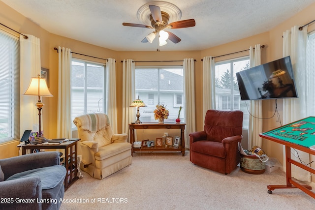 sitting room featuring ceiling fan, light carpet, and a textured ceiling