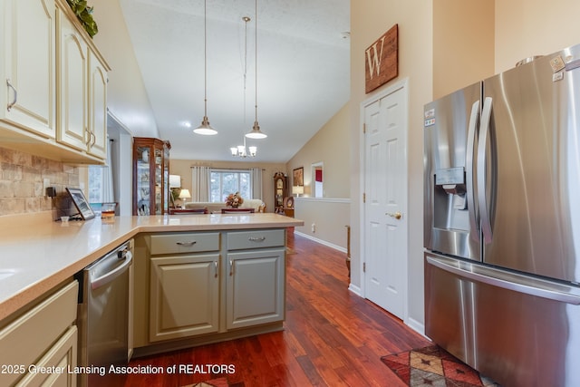 kitchen with appliances with stainless steel finishes, decorative light fixtures, tasteful backsplash, lofted ceiling, and dark hardwood / wood-style flooring