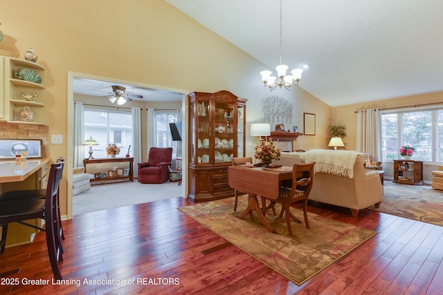 dining area featuring ceiling fan with notable chandelier, wood-type flooring, and high vaulted ceiling