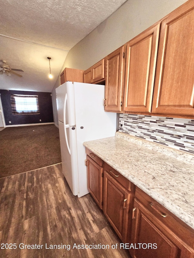 kitchen featuring white fridge, dark hardwood / wood-style floors, light stone counters, and a textured ceiling