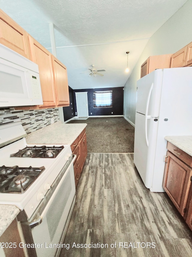 kitchen featuring vaulted ceiling, dark hardwood / wood-style floors, pendant lighting, white appliances, and decorative backsplash