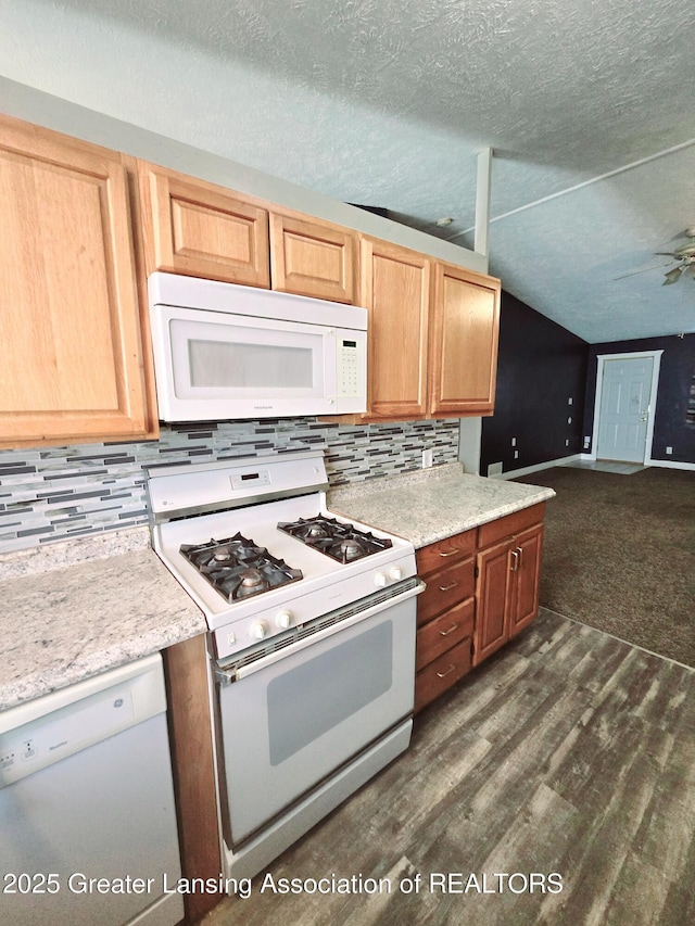 kitchen with dark wood-type flooring, lofted ceiling, a textured ceiling, white appliances, and decorative backsplash