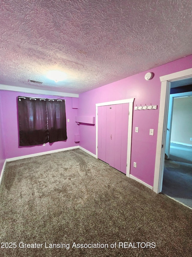 unfurnished bedroom with carpet flooring, a textured ceiling, and a closet