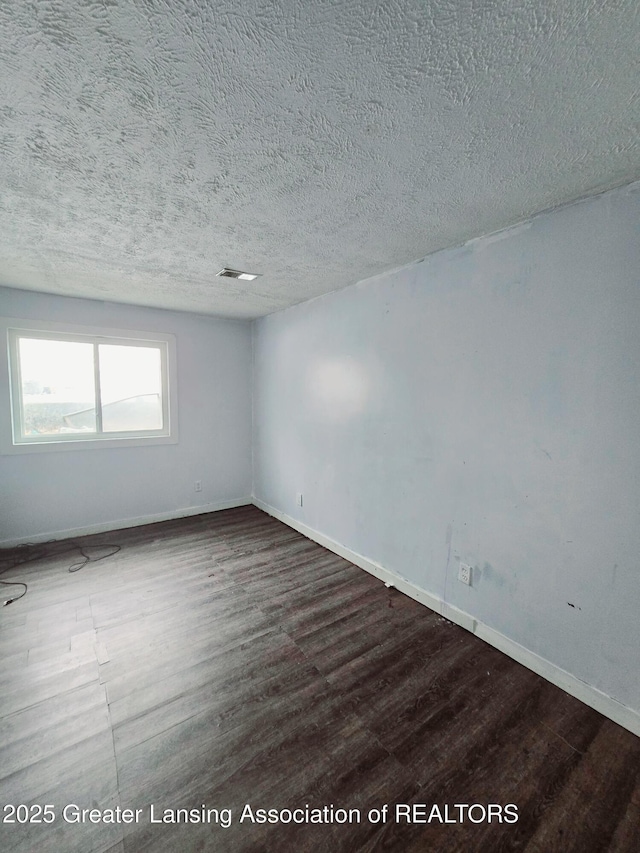 spare room with dark wood-type flooring and a textured ceiling