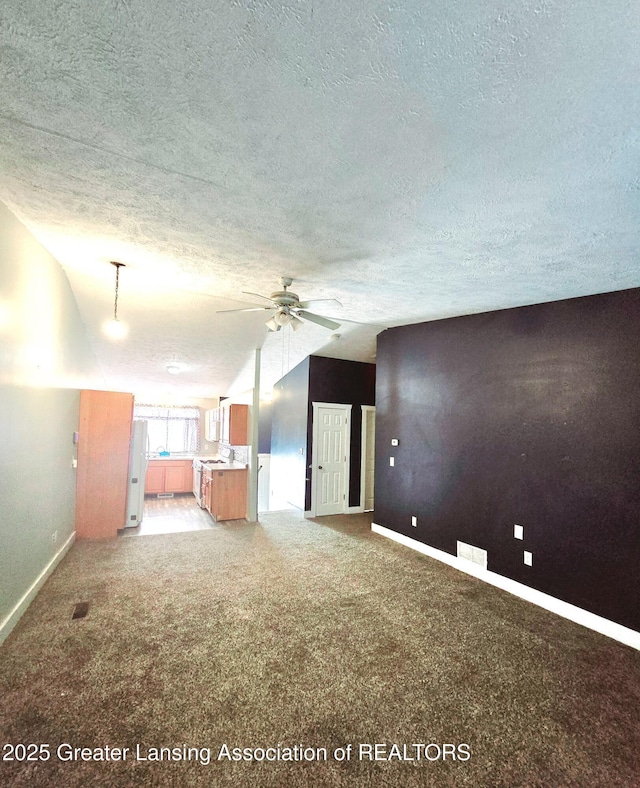 unfurnished living room with ceiling fan, carpet, and a textured ceiling