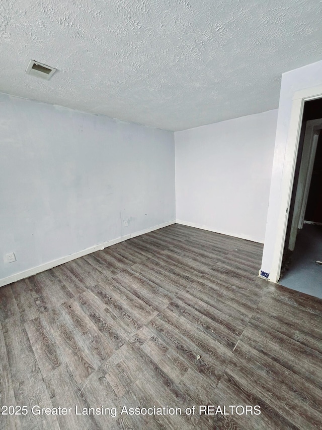 empty room featuring dark wood-type flooring and a textured ceiling