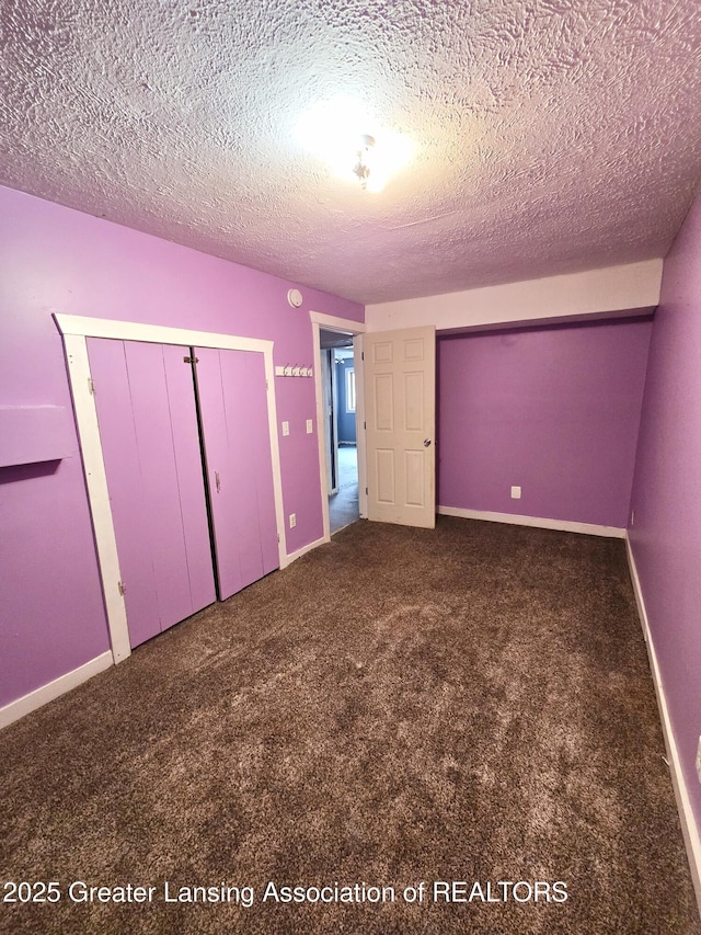 unfurnished bedroom featuring dark carpet, a closet, and a textured ceiling