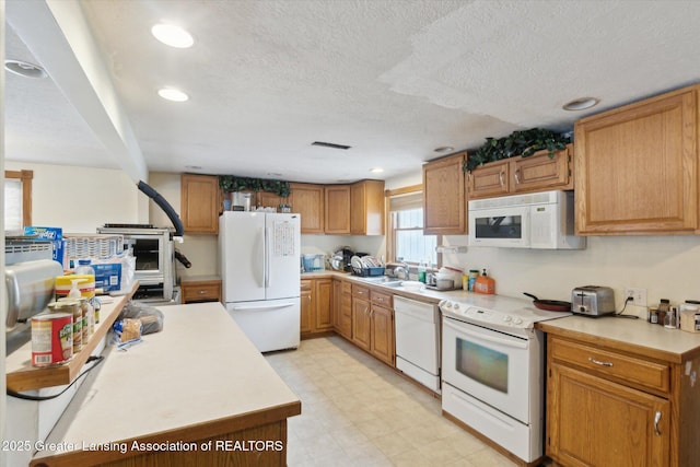 kitchen featuring white appliances, sink, and a textured ceiling