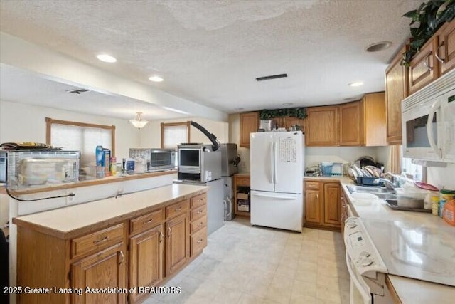 kitchen featuring sink, white appliances, and a textured ceiling