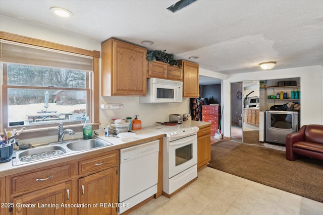 kitchen with washer and dryer, sink, a textured ceiling, and white appliances