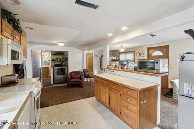 kitchen with white appliances, washer / clothes dryer, light colored carpet, and a kitchen island